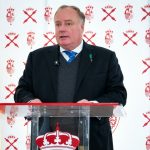 Don Carlos Javier de Borbón Parma, en el centro de la imagen con un fondo con su escudo real y cruces de borgoña junto a una bandera de España, pronuncia su discurso en Madrid el 14 de marzo de 2026
