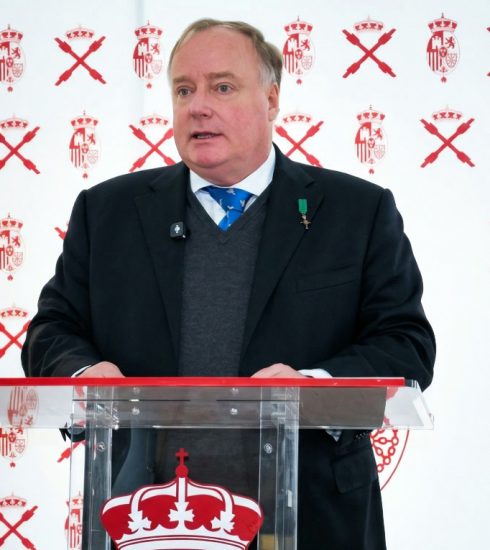 Don Carlos Javier de Borbón Parma, en el centro de la imagen con un fondo con su escudo real y cruces de borgoña junto a una bandera de España, pronuncia su discurso en Madrid el 14 de marzo de 2026